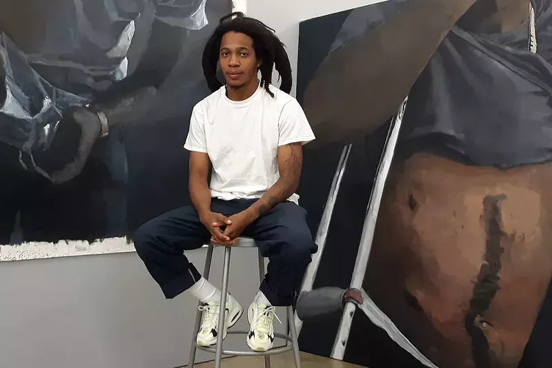 Image: Artist Reginald O'Neal sits surrounded by his paintings.