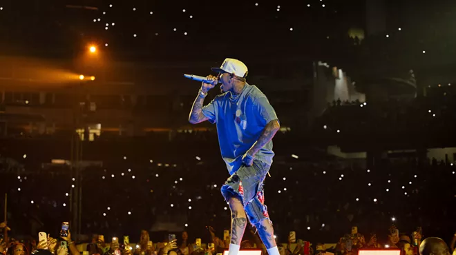 A man singing with a mic on stage in front of a crowd.