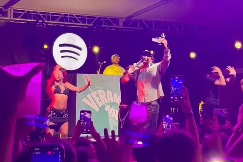 Image: A man performing on stage with a Spotify logo in the back.