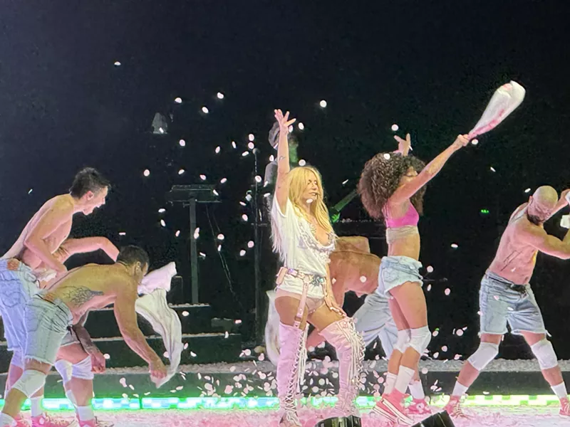 Image: Woman on stage wearing white shorts and high boots.
