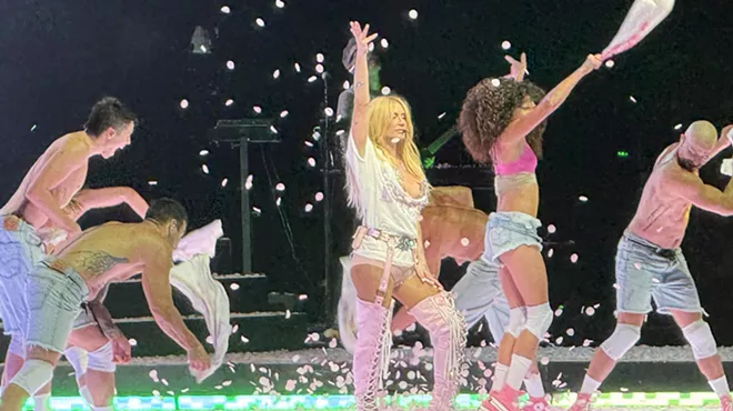 Woman on stage wearing white shorts and high boots.