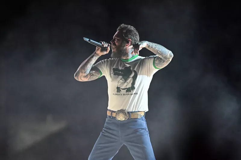 Image: Post Malone performs in jeans and a Silver Springs Florida T-shirt featuing a cartoon alligator