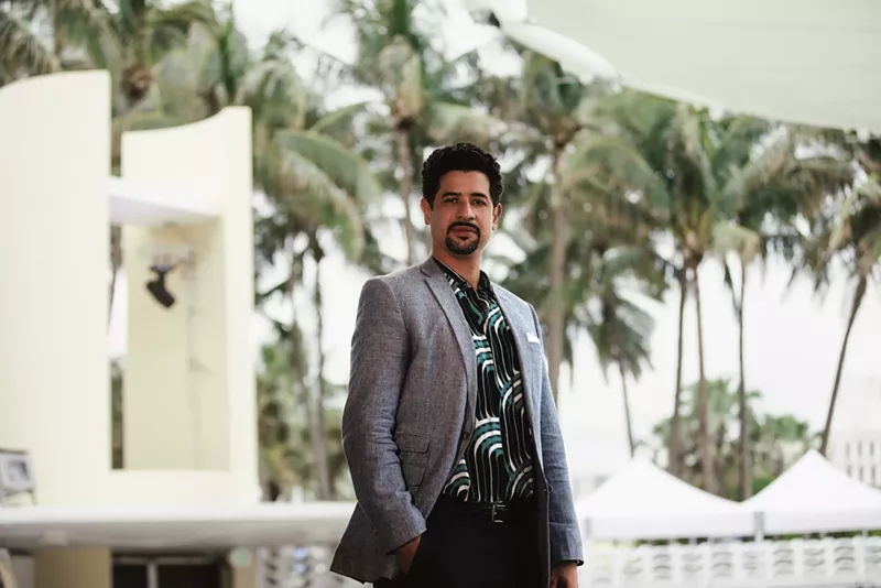Image: Adam Ganuza in a blazer in front of palm trees