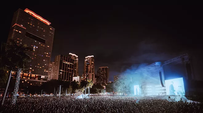 a huge crowd at an outdoor venue with the downtown Miami skyline in the background