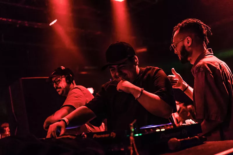 Image: A DJ performing under red lights.
