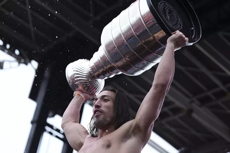 Image: A soggy, shirtless hockey player named Ryan Lomberg hoists the Stanley Cup trophy over his head