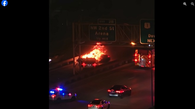 A car engulfed in flames at night on I-95 in downtown Miami