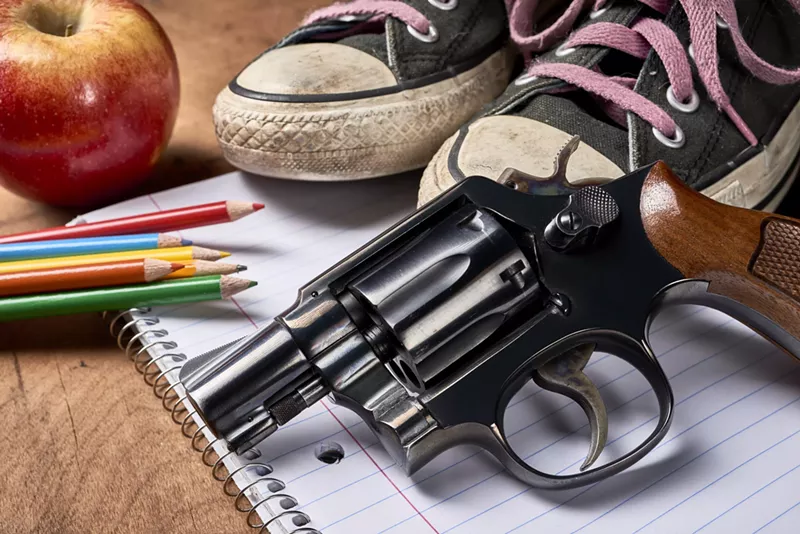 Image: A gun next school supplies and an apple