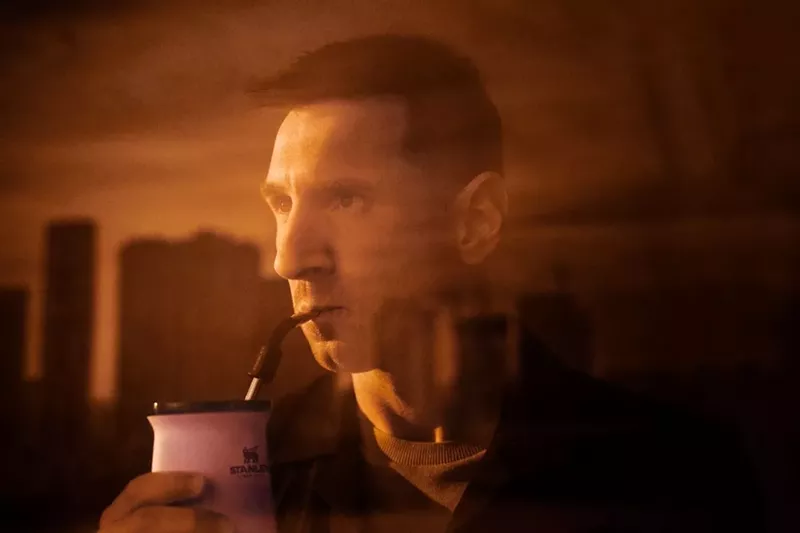 Image: sepia-toned image of leonel messi drinking out of an insulated cup through a straw