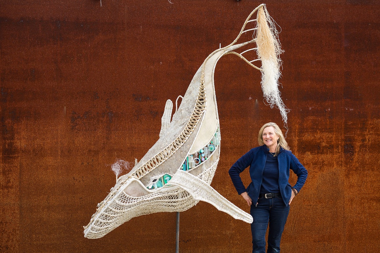 Artist Cindy Pease Roe poses next to her 250-pound whale sculpture made of marine debris.