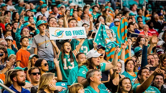Dolphins fans wearing teal jerseys in the stands at Hard Rock Stadium.