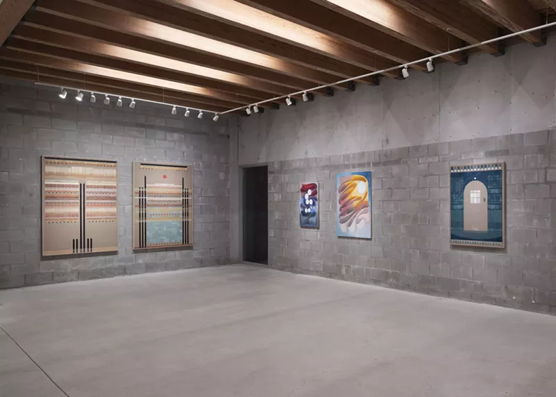 Image: art hangs on gray concrete walls in a museum