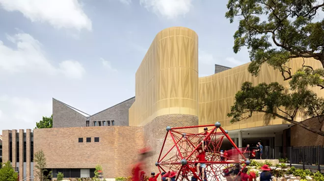 children play on a red jungle gym in front of a building