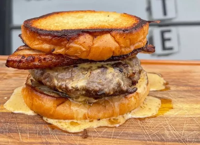 Image: A burger with meat and cheese on a wooden serving platter