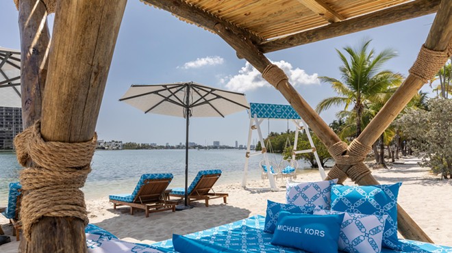 A beach club with blue chairs facing the ocean