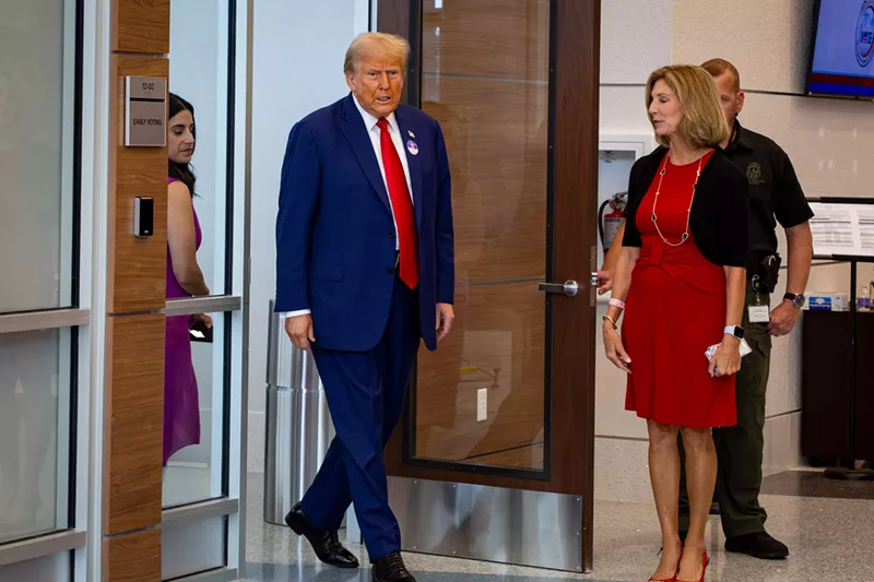 Image: Trump walks into a local Palm Beach County polling place wearing signature suit and red tie