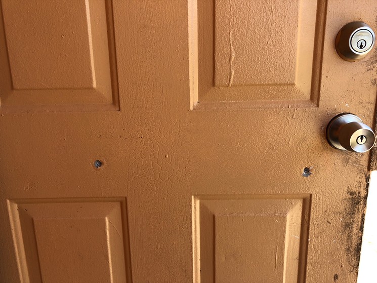 A crime scene photo from the shooting of Juvon Simon shows two bullet holes through the apartment door. - PHOTO COURTESY OF DAN KAUFMAN AND CHRISTOPHER MARLOWE