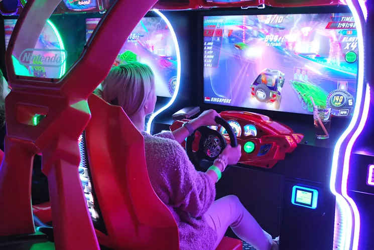 A young woman playing a racing arcade game