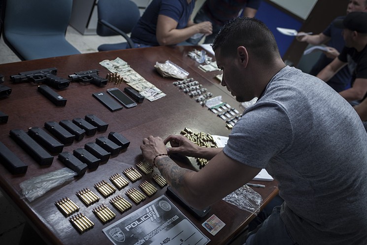 At the police station in Guaynabo, officers lay out the contraband found in one evening in a small suburb of San Juan. "This is a daily theme here in Puerto Rico," one officer says. - PHOTO BY DOUGLAS HOOK