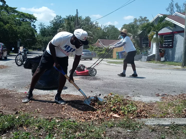 Ashley Toussaint (left) and Jonathan Salomon (right) clean up the sidewalk behind Toussaint L'Ouverture Elementary. - PHOTO BY JOSHUA CEBALLOS