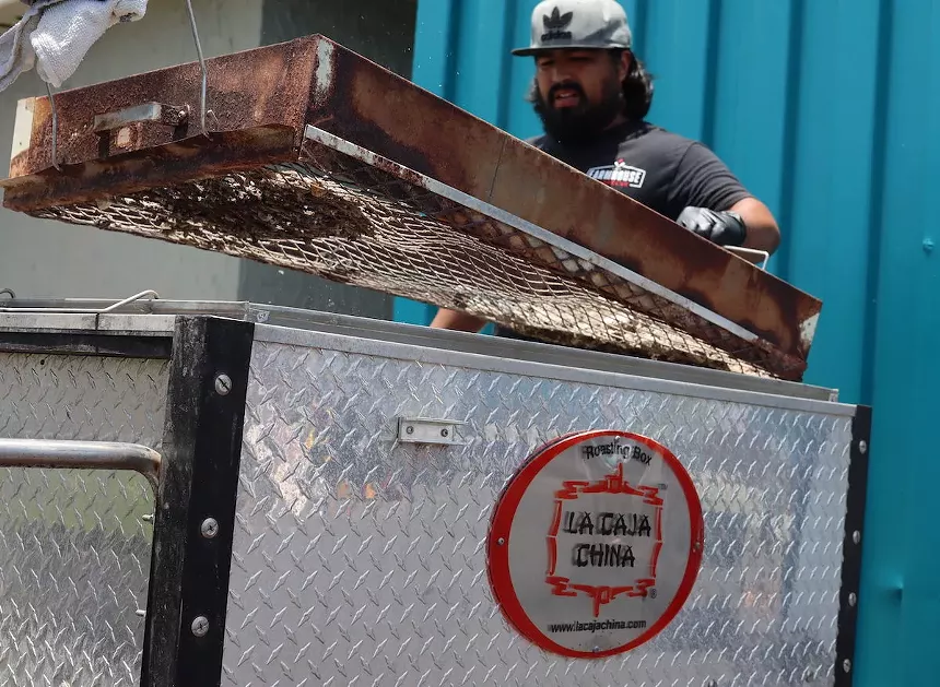 Farmhouse BBQ chef/owner Jorge Duran mans the Caja China at his restaurant inside Beat Culture brewery. - PHOTO BY NICOLE DANNA