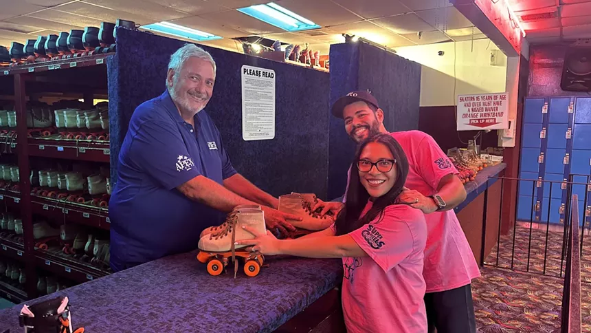 Super Wheels' former owner Thomas Mitchell handing skate to Miami Roller Rink owners Gabe Colon and Pam Mostacero