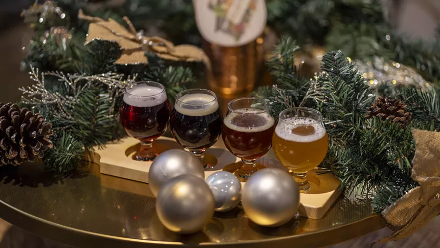 A beer flight at Biscayne Bay Brewing Company's holiday pop-up bar sits on a gold platter surrounded by a holiday garland and silver ornaments.