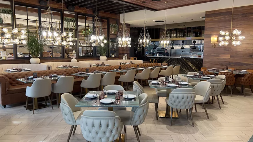 The light blue seats fill the dimly lit dining room of Baires Grill in Downtown Doral