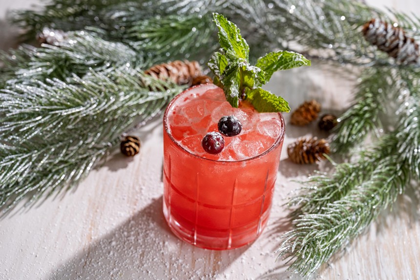 This holiday cocktail is red and topped with cranberries and mint