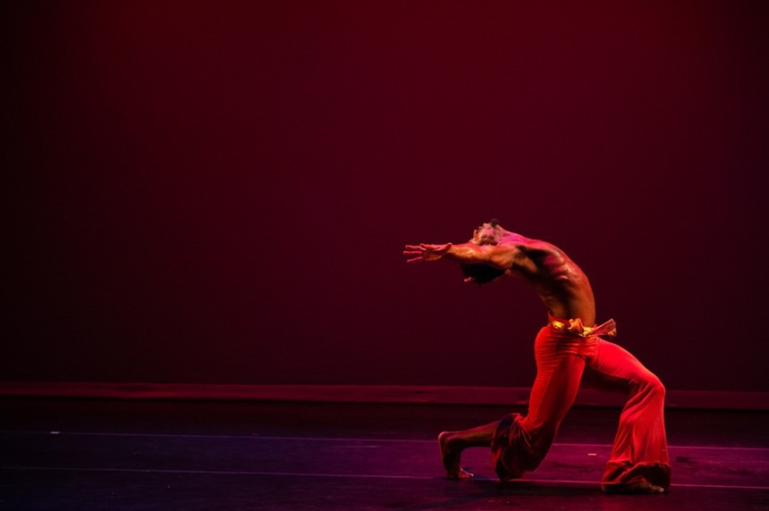 Male dancer in red pants stretches his arms back