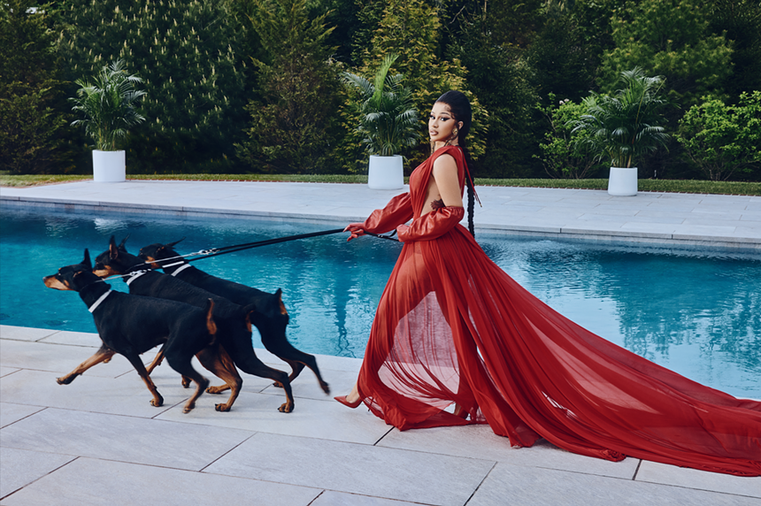 Cardi B walks three dogs on a leash next to a pool