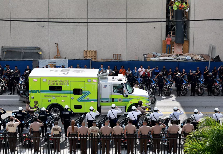 Officers salute an ambulance carrying the body of a policeman killed during a hotel raid