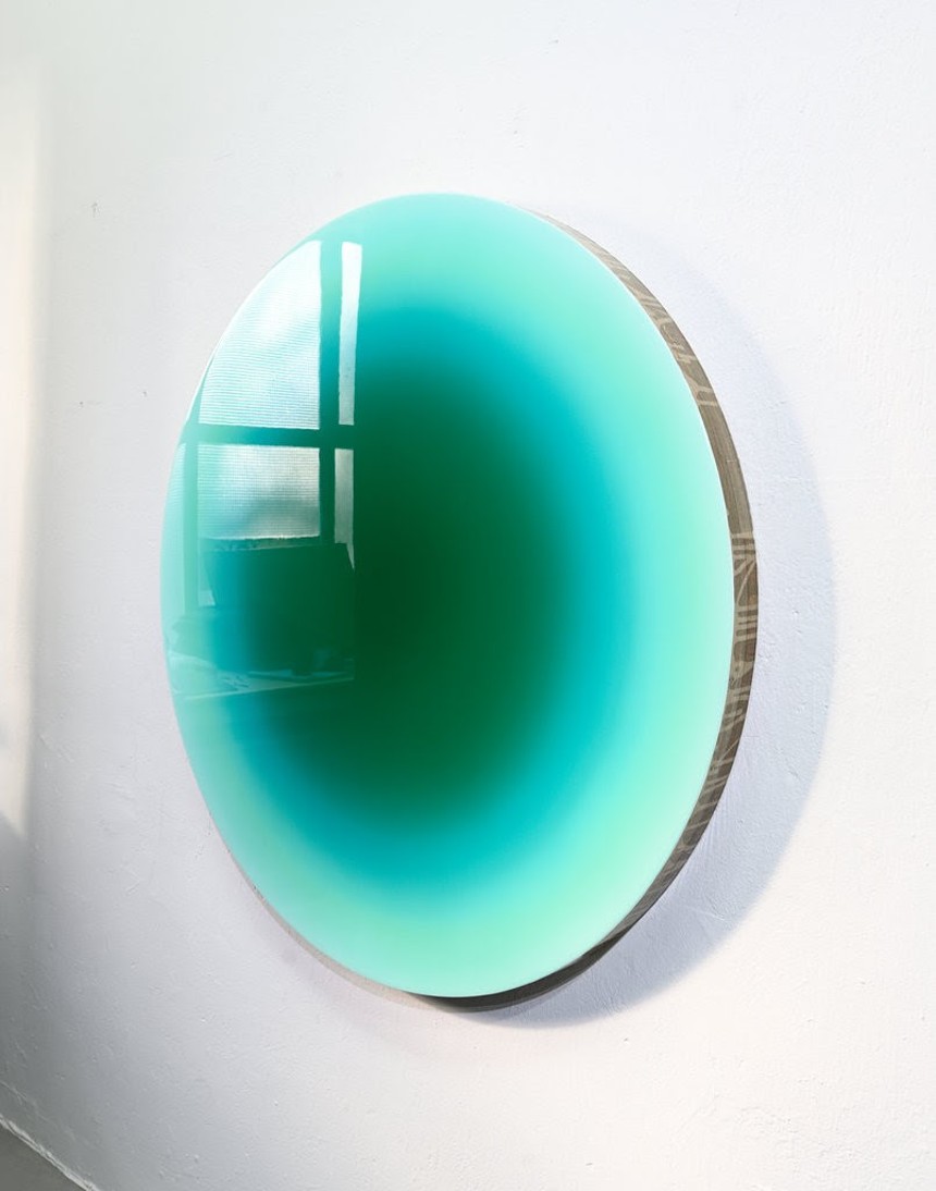 Circular green art work with a shiny reflective surface
