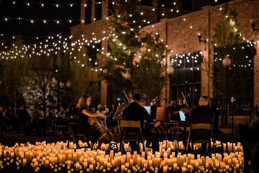 A string quarter performing surrounded by candles