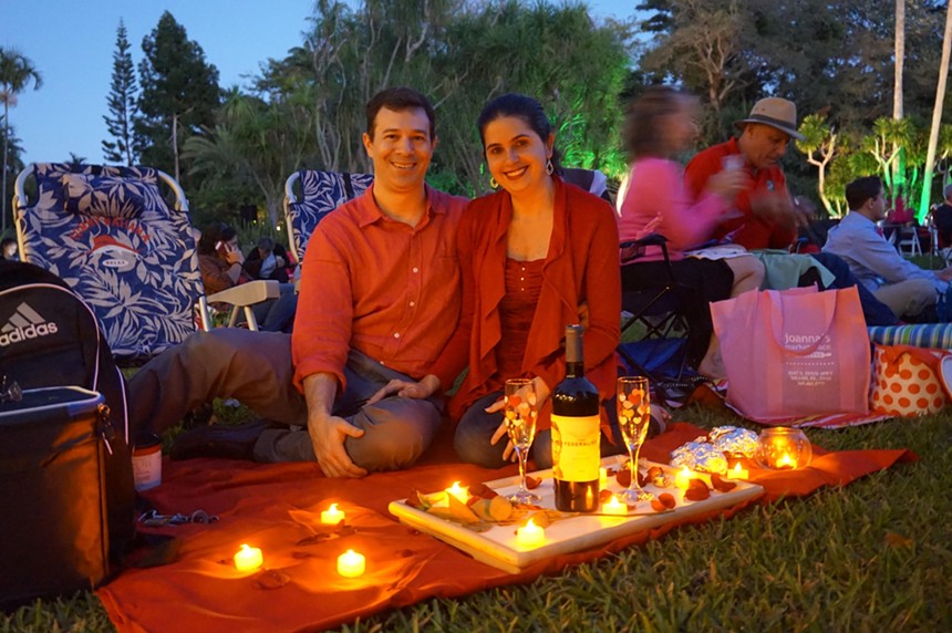 A couple sitting on a blanket over the grass