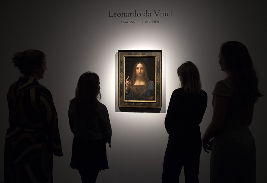Leonardo da Vinci's Salvator Mundi hanging on the wall as four people look on
