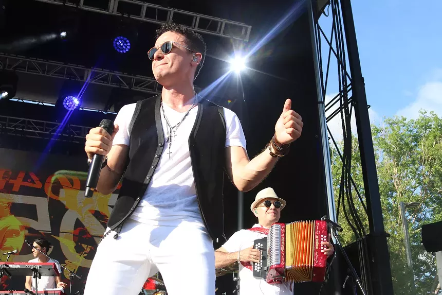 Man performing on stage with a band behind him