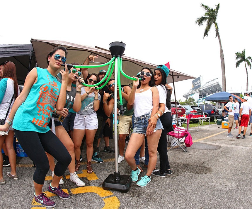 Miami Dolphins fans gather around a beer funnel with multiple tubes