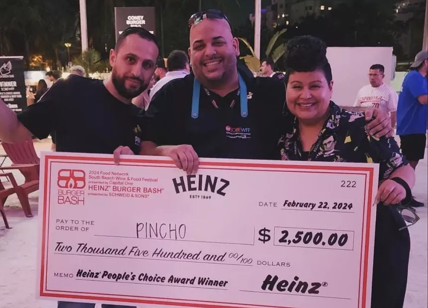 Three people hold a giant check