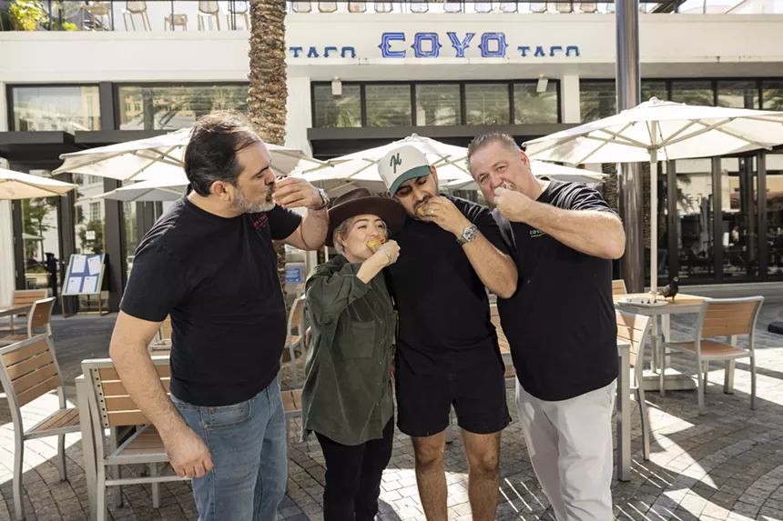 Three people wearing black eating a taco