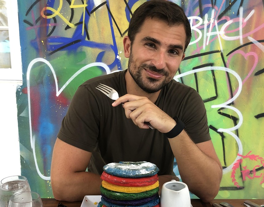 A man eating colorful pancakes with a fork
