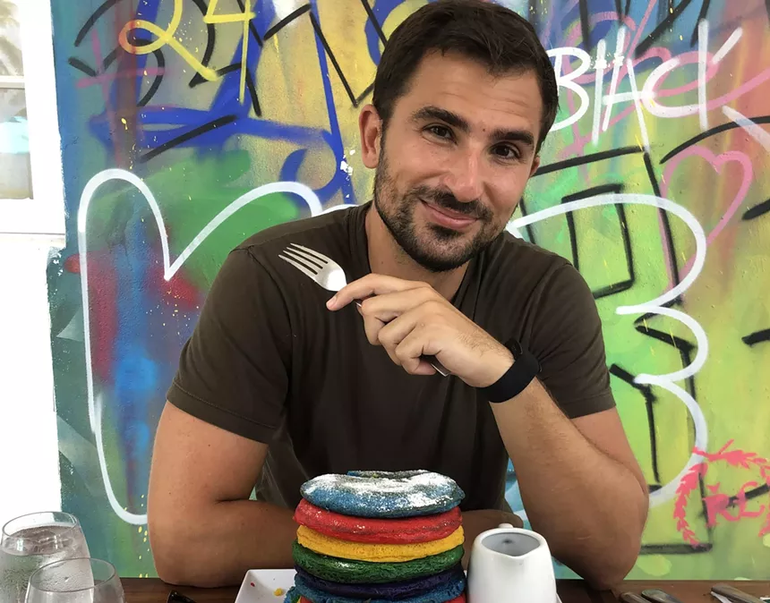 A man eating colorful pancakes with a fork