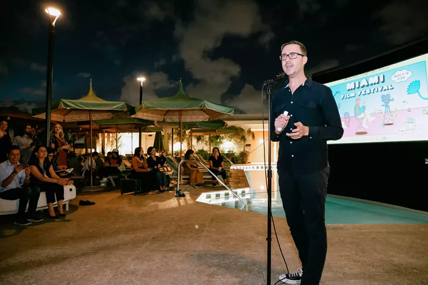 James Woolley standing in front of a microphone speaking to a large group of people