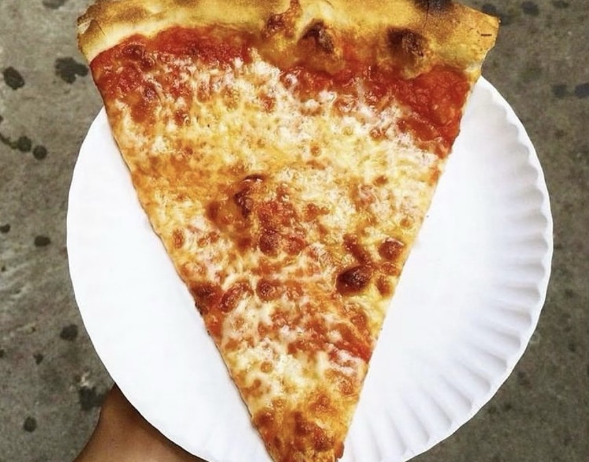 A pizza slice on a white cardboard plate