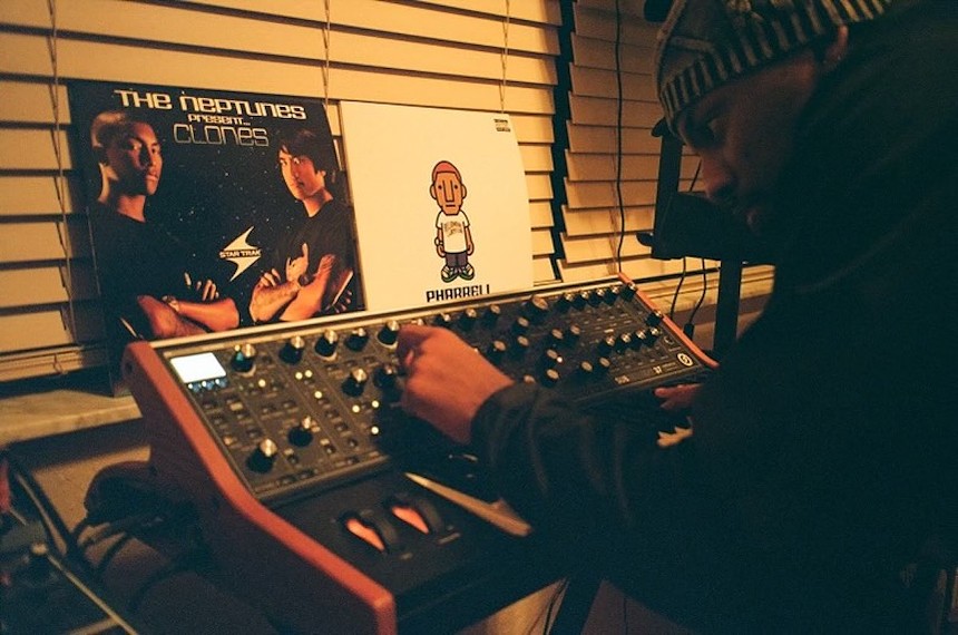 Justin Wiggins turning knobs on his synthesizer at his studio