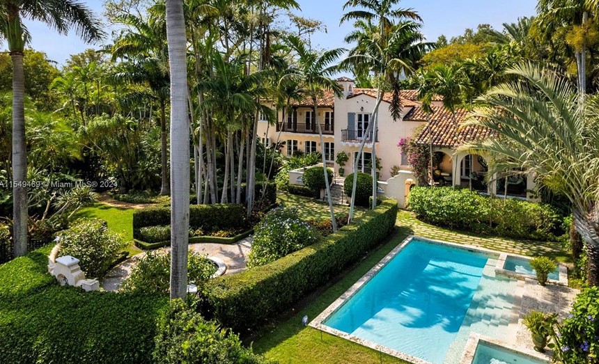 a photo from a real estate listing showing the exterior of an opulent house with manicured garden and swimming pool