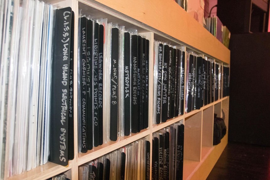 A row on vinyl records on a shelf labeled by genre