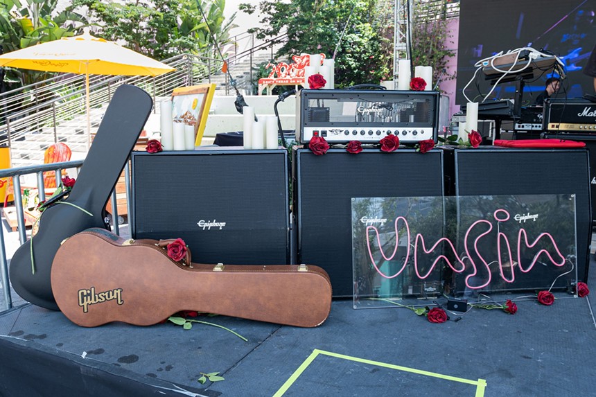 A stage with a guitar case and Unsin logo