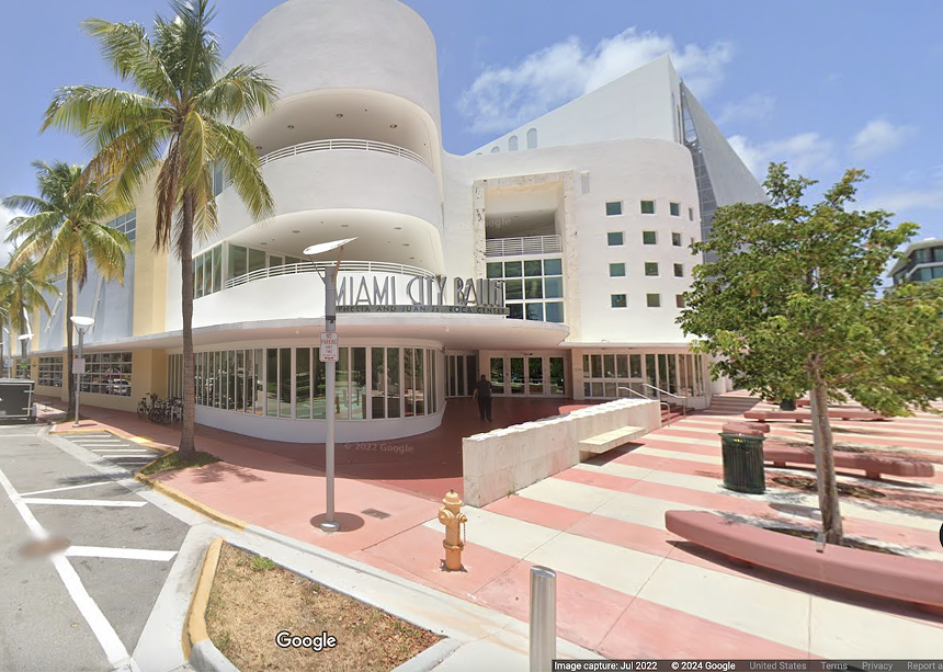 White exterior of the Miami City Ballet building on palm-tree-lined road in Miami Beach