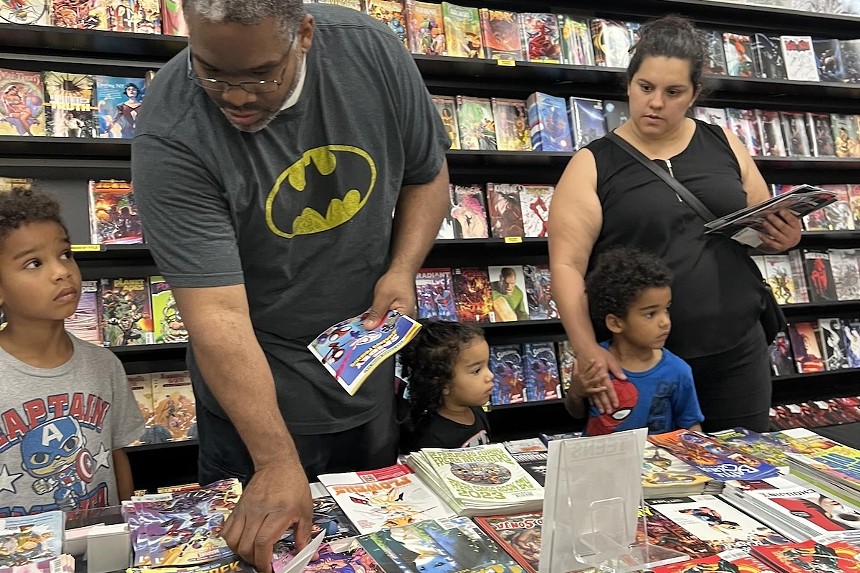 A mother and father with their three young children browsing through comic books